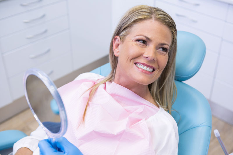 Woman in office chair smiling at dentist.