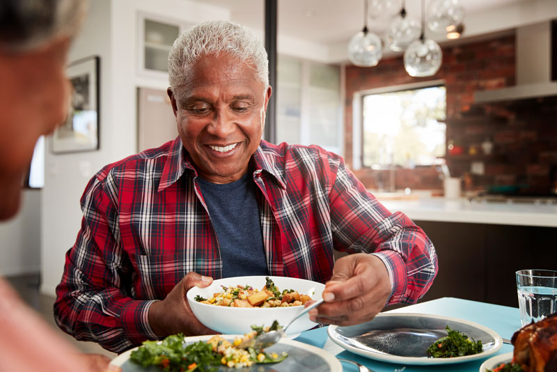Loose dentures man eating at as table with family happy