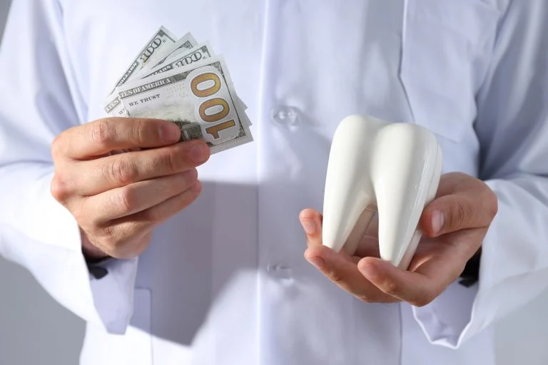 Dollars and tooth in hands of dentist