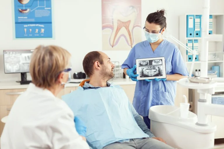 Dentist showing dental image on a tablet in a modern clinic to a patient